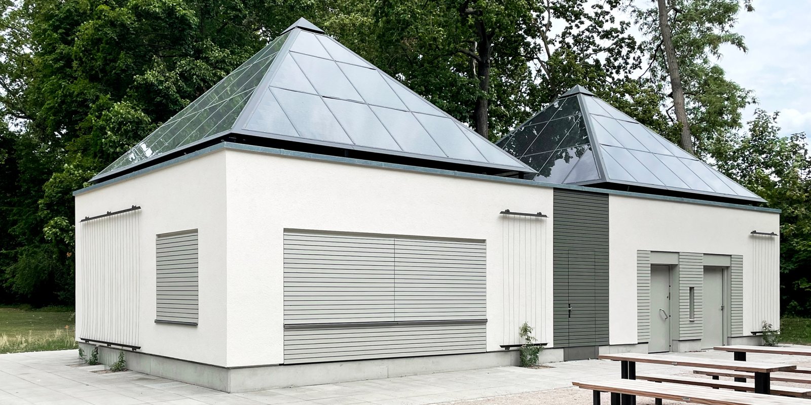 Kiosk im Unteren Schlossgarten Stuttgart mit heller Fassade und zwei pyramidenförmigen Photovoltaikdächern