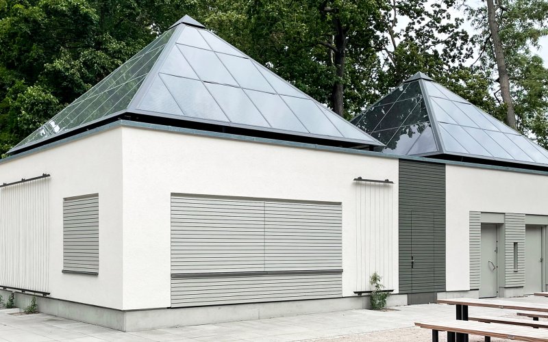 Kiosk im Unteren Schlossgarten Stuttgart mit heller Fassade und zwei pyramidenförmigen Photovoltaikdächern