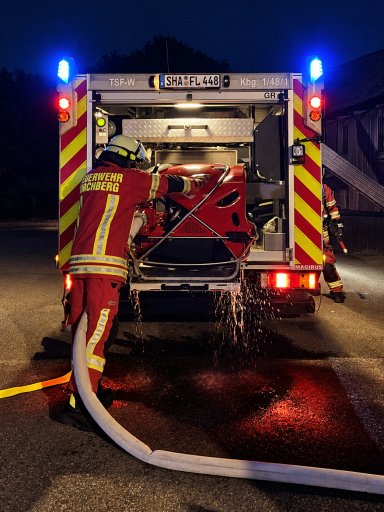 Feuerwehrmann der Feuerwehr Kirchberg entnimmt während der gemeinsamen Übung einen Schlauch aus einem Löschfahrzeug.
