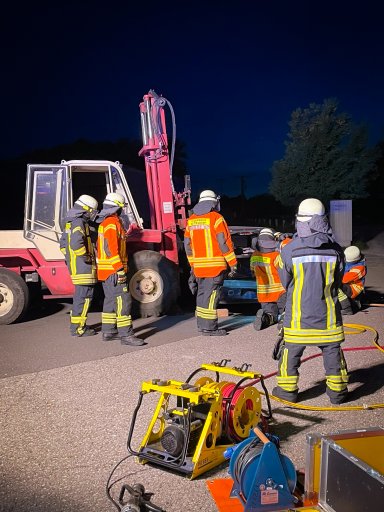 Einsatzkräfte der Feuerwehr Satteldorf arbeiten gemeinsam am simulierten Verkehrsunfall zwischen einem Stapler und einem Auto.
